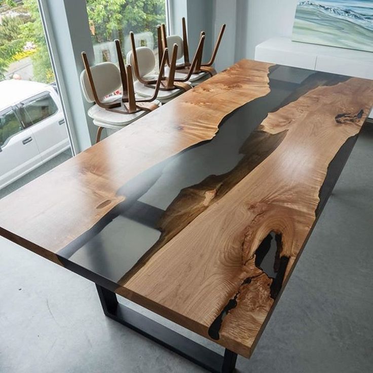 Wooden dining table with black epoxy resin inlay in a modern interior setting in river desgin 